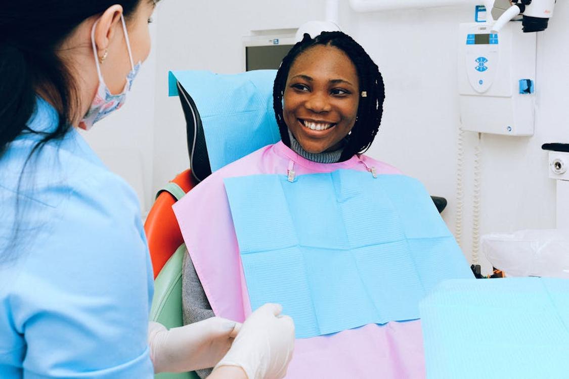 a smiling woman receives dental check up from a practitioner in modern clinic - Plano Cosmetic Dental Care: Your Complete Smile Makeover