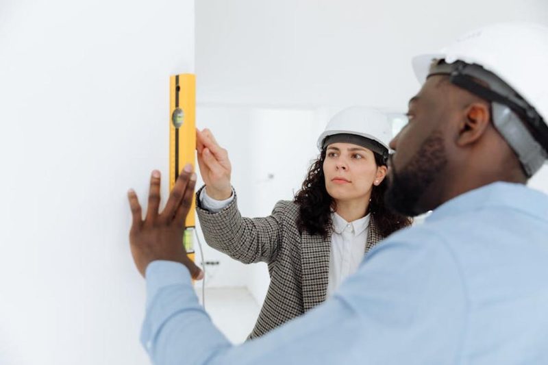 two contractors using a level tool on a wall indoors 800x533 - Miami Construction Excellence: Professional Standards