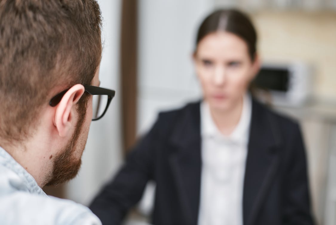 A Man Wearing Black Framed Eyeglasses in Front of a Woman in Black Blazer - Exploring How Staffing Agencies Build Diverse Teams
