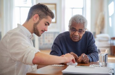 a guy giving medicine to a senior 380x250 - 5 Reasons Pain Relievers Work Differently for People