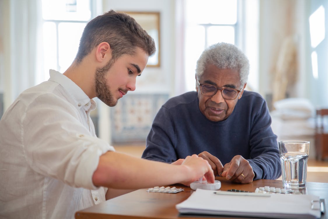 a guy giving medicine to a senior - 5 Reasons Pain Relievers Work Differently for People