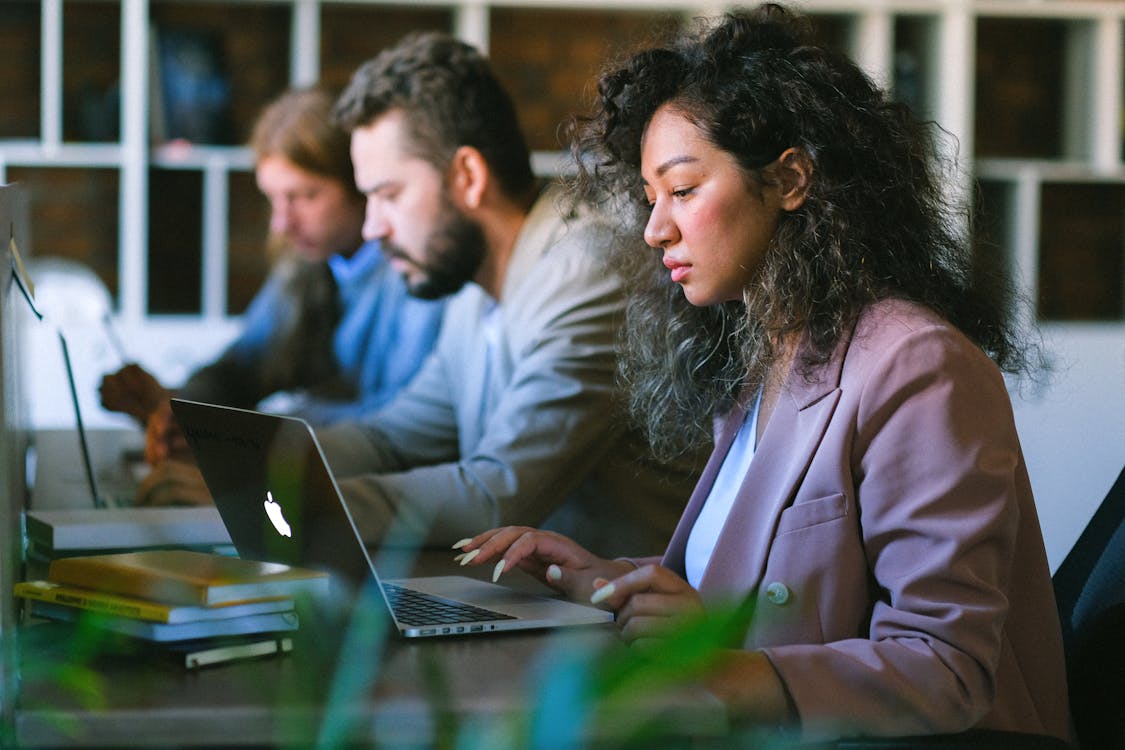 Focused colleagues working on laptops in office - How to Scale Brand Strategy Efficiently Through AI