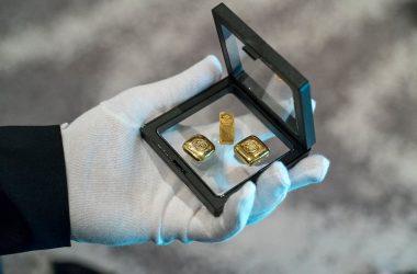 a person wearing gloves holding a glass frame with gold bars 380x250 - How to Choose the Right Gold Assets for Your Goals
