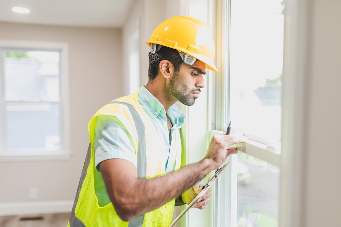 a man in yellow hard hat checking the windows - Can Pest Issues Delay Property Sales? Discover Why