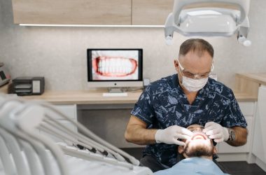 Dentist in surgical mask performing a dental check up on a patient 380x250 - The IRS Just Raised HSA Limits for 2026 — Here's Why That Matters for Texas Patients Considering Full-Mouth Implants