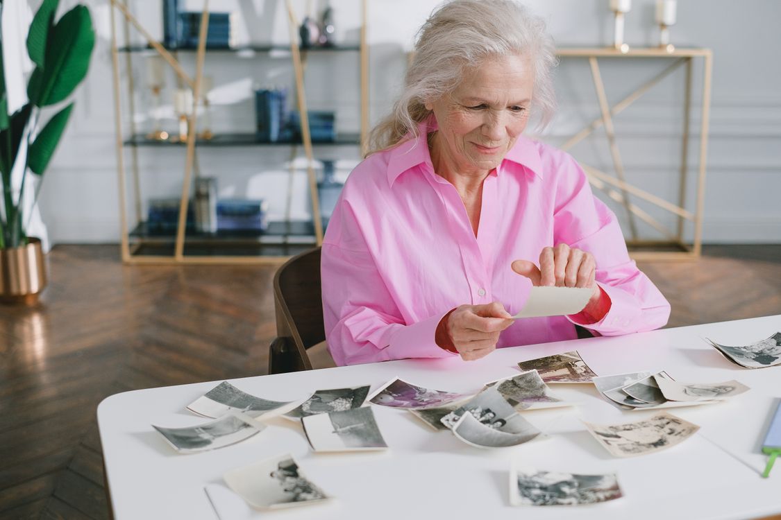 a senior woman looking at photographs on a table - San Diego's Dementia Forecast Is Changing How Families Plan Elder Care